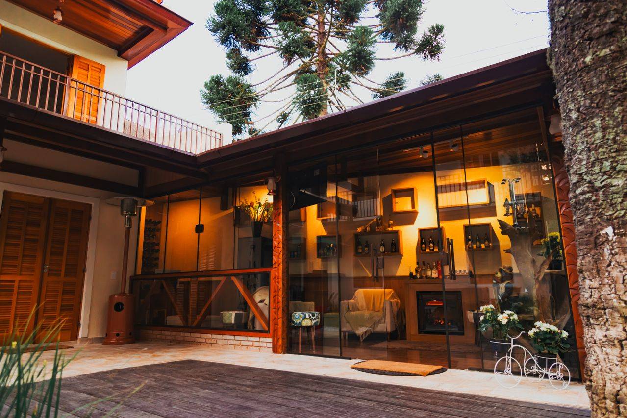 Modern house with a cozy patio and glass wall, featuring indoor seating and decor.