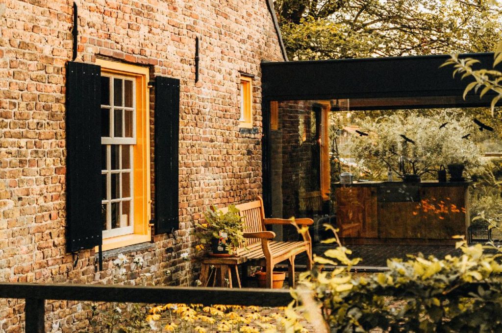 Contemporary glass box extension with slim black frames joined to a period red brick house