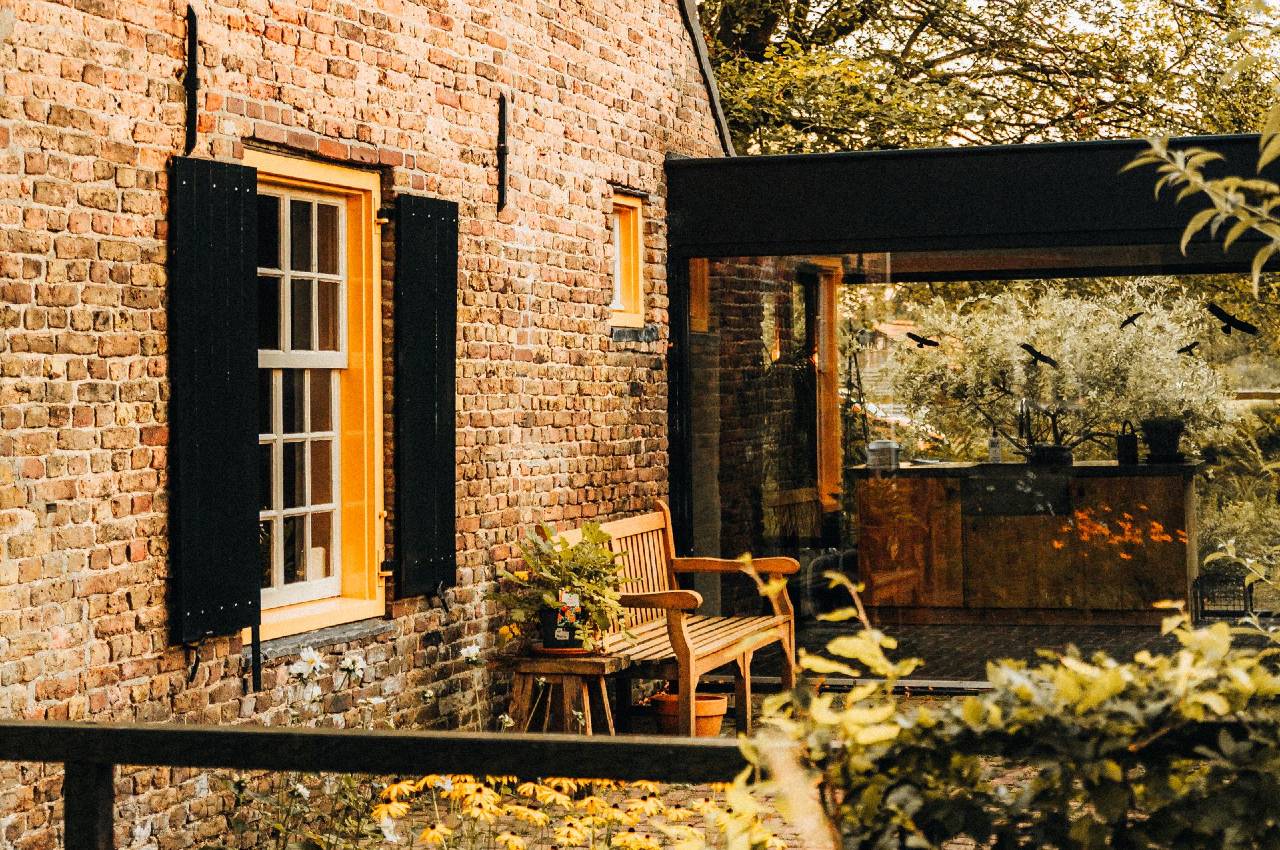 A picturesque rustic house with a thatched roof and lush garden, bathed in warm autumn glow.