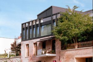 A picturesque canal house with flourishing greenery, and a sunny summer day.